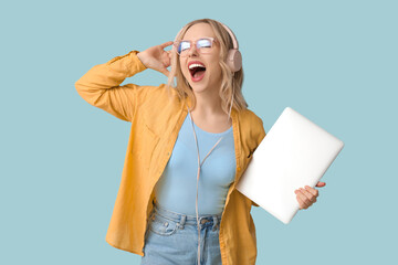 Sticker - Pretty young woman with modern laptop and headphones listening to music on blue background