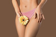 Young woman in panties with beautiful yellow flower on brown background