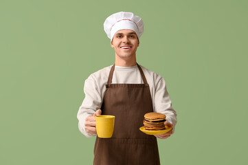 Canvas Print - Young man with tasty homemade pancakes and tea on green background