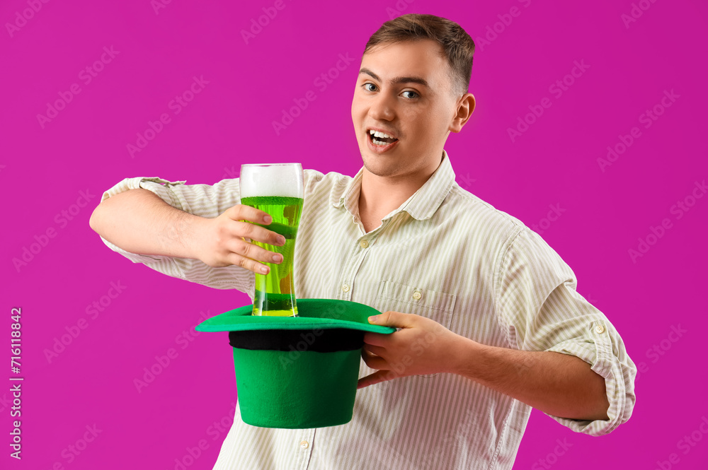 Young man with beer and Leprechaun's hat on purple background. St. Patrick's Day celebration