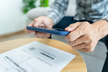 business man use phone to scan barcode or qr codes to pay credit card bill after receiving document 