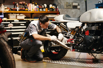 Wall Mural - Mechanic in uniform concentrated on diagnosing and fixing common problems with motorcycle