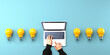 © Tierney - Person using a laptop computer with light bulbs from above