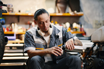 Wall Mural - Mechanic pouring himself cup of coffee from thermos when having lunch break