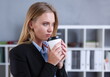 © H_Ko - Smiling business woman drinking coffee from a paper cup in the office portrait looking into the camera holding in her hand and resting during a break.