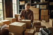 Man packing items into boxes Male courier service delivery goods online store. Portrait with selective focus. Online salesperson packing boxes for dispatch to customers, online working from home