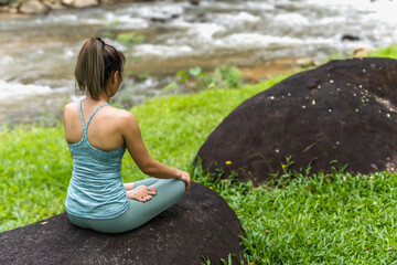 Back view woman doing yoga exercise near river