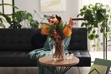 Wall Mural - Vase with bouquet of beautiful leucospermum flowers and air freshener on side table near black sofa in room