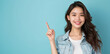 © CraftyImago - Asian woman presents, pointing with copy space light blue background, portrait captures the beauty, confidence, and elegance of a young and attractive Asian model.