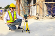 © ฺฺฺBoonterm - Female engineer foreman sitting holds laptop computer setup and checks  modern technology tools laser level and vertical marker (Plum Bob) on tripod at construction site, condominium building.