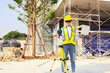 © ฺฺฺBoonterm - Female engineer foreman holds laptop computer setup and checks  modern technology tools laser level and vertical marker (Plum Bob) on tripod at construction site, condominium building.