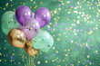 bunch of balloons isolated on green background with blurred confetti all around. Lilac, green and gold colors