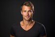 © Anzhela - Portrait handsome tanned smiling young man with brown hair in black T-shirt on dark background