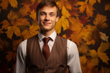 Wall Mural - Portrait of a cheerful man in his 20s dressed in a polished vest against a background of autumn leaves. AI Generation