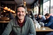 © CogniLens - Portrait of a joyful man in his 40s sporting a long-sleeved thermal undershirt against a bustling city cafe. AI Generation