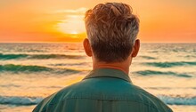 The Back Of A Man's Head As He Stands On A Beach With The Sun Setting Over The Ocean And Waves Coming In From The Water And Behind Him.