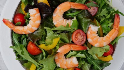 Poster - Vegetarian fresh salad tomatoes arugula pepper shrimps rotating on plate. Close up. Top view