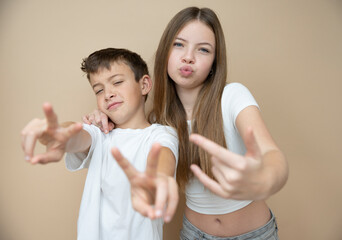 beautiful pretty 14 years old girl with her cute and cool 11 years old brother in front of brown bac