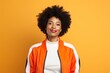 © CogniLens - Portrait of a content afro-american woman in her 40s sporting a stylish varsity jacket against a pastel orange background. AI Generation