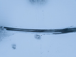 Wall Mural - Aerial view of road through snow covered landscape.