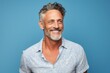 © CogniLens - Portrait of a happy man in his 50s donning a trendy cropped top against a soft blue background. AI Generation