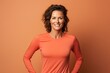 © CogniLens - Portrait of a content woman in her 40s wearing a moisture-wicking running shirt against a soft orange background. AI Generation