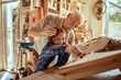 © Marko Geber - Grandfather and grandson working on a model boat in a woodworking workshop