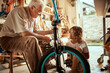 © Marko Geber - Grandfather and grandson fixing a bike in the garage