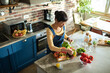© Marko Geber - Happy woman preparing a salad with fresh vegetables in a modern kitchen