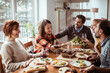 © Davor - Group of friends enjoying a meal together indoors with winter scenery outside