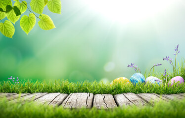 Wall Mural - Painted easter eggs in the grass celebrating a Happy Easter in spring with a green grass meadow, tree leaves and bright sunlit cool background & rustic wooden bench to display products.