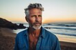 © CogniLens - Portrait of a tender man in his 50s sporting a versatile denim shirt against a stunning sunset beach background. AI Generation