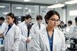 © Visal - Beautiful young woman scientist wearing white coat and glasses in modern Medical Science Laboratory with Team of Specialists on background.