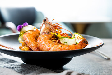 Canvas Print - grilled prawns with onion and lemon in black plate on table