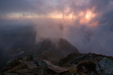 Wall Mural - Sunny sunrise in autumn mountains. Mountains in a fog illuminated by rising sun. Autumn landscape with vivid sunlight. 