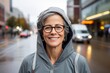 Portrait of a grinning woman in her 50s sporting a comfortable hoodie against a bustling city street background. AI Generation