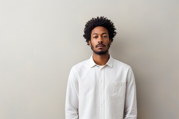 Portrait of a tender afro-american man in his 20s wearing a simple cotton shirt against a minimalist or empty room background. AI Generation