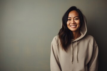 Canvas Print - Portrait of a satisfied asian woman in her 30s sporting a comfortable hoodie against a light wood minimalistic setup. AI Generation