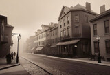 Fototapeta Uliczki - Vintage black and white (sepia) photograph of the old town of the 19th century with fog and smoke, streets in the old town, Old photograph,