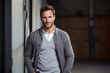 Wall Mural - Portrait of a glad man in his 30s wearing a chic cardigan against a empty modern loft background. AI Generation