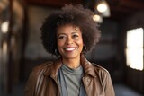 Fototapeta Uliczki - Portrait of a grinning afro-american woman in her 60s wearing a trendy bomber jacket against a empty modern loft background. AI Generation