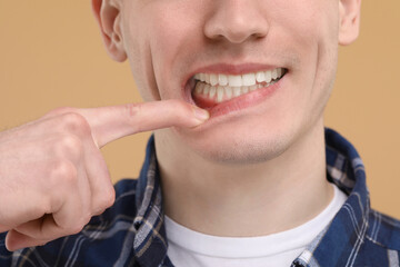 Wall Mural - Man showing his clean teeth on beige background, closeup