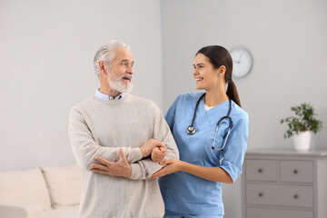 Canvas Print - Smiling nurse supporting elderly patient in hospital