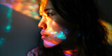 Fototapeta  - Profile of a contemplative woman with colorful light patterns dancing on her skin, creating a vibrant look