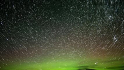 Wall Mural - a time lapse of stars with star-trails move through the night sky that has aurora and some clouds al