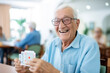 Happy senior man playing card games with friends, activity social networking in nurs home. Concept enjoying playtime together in poker game, old men