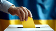 The hand of a voter dropping his vote into the ballot box. The concept of elections. The flag of Ukraine is in the background. Elections in Ukraine 2024.