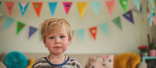 Sticker - Blond boy gazes into camera while hanging colorful party pennants on living room wall.