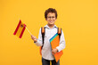 © Prostock-studio - Smiling boy with Spanish flag and school folders, bright yellow bacdrop