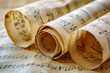 Rolled sheets with music notes on light background, close up.